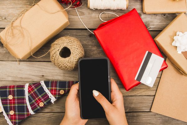 woman-s-hand-with-smartphone-near-plastic-card-set-decorations