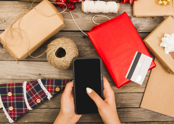 woman-s-hand-with-smartphone-near-plastic-card-set-decorations
